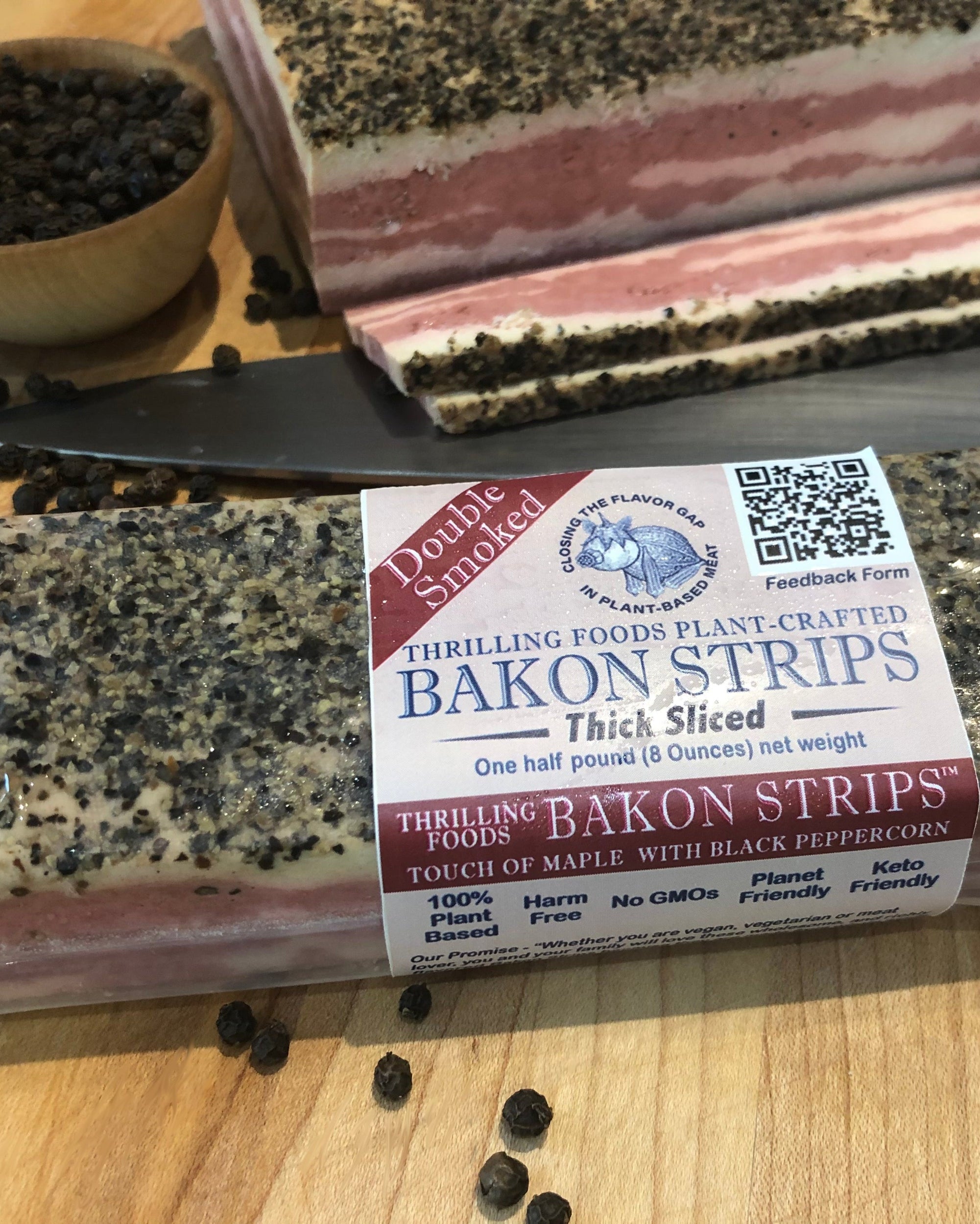 Packaged Thrilling Bakon strips on a wooden surface, with visible black pepper sprinkled on top.